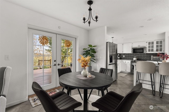 dining area with french doors, dark tile patterned flooring, and an inviting chandelier