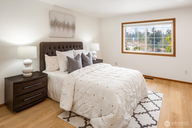 bedroom featuring light wood-style floors, visible vents, and baseboards