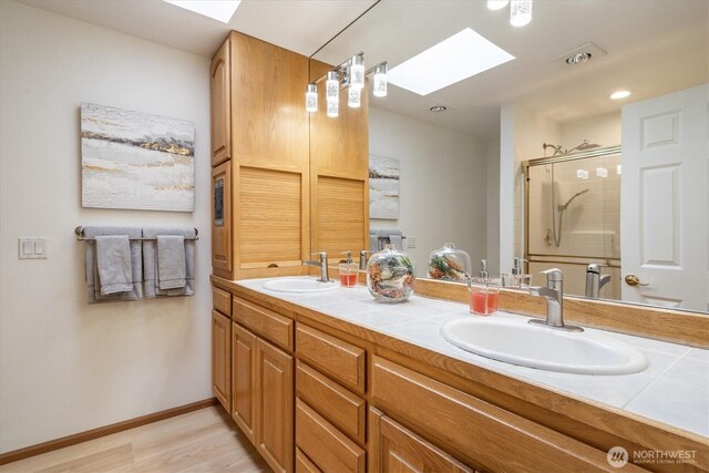 full bathroom featuring a skylight, a sink, and a stall shower