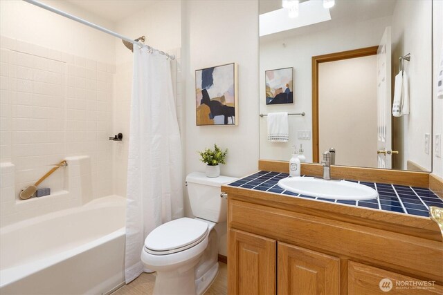 bathroom featuring toilet, shower / bath combination with curtain, and vanity