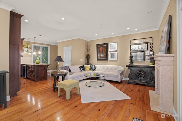 living room with a notable chandelier, light wood-type flooring, beverage cooler, and ornamental molding