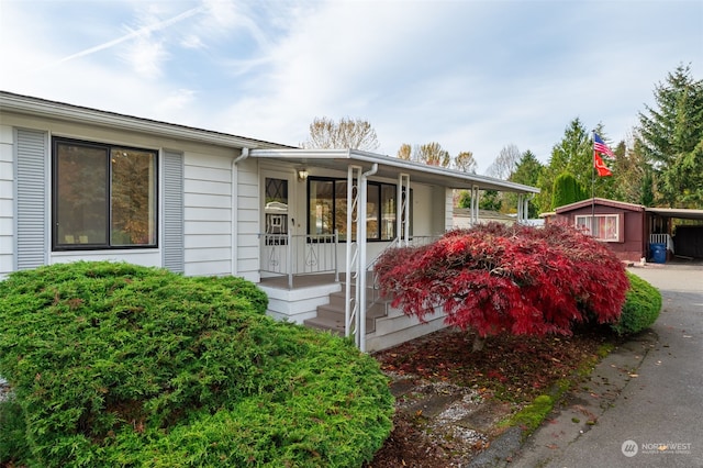 single story home featuring a storage shed and a porch