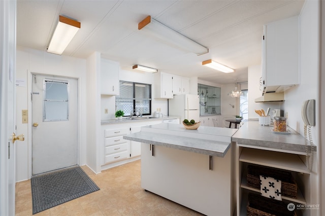 kitchen featuring a breakfast bar, kitchen peninsula, sink, white cabinets, and white refrigerator