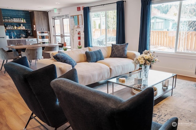 living room featuring light hardwood / wood-style floors, plenty of natural light, and indoor bar