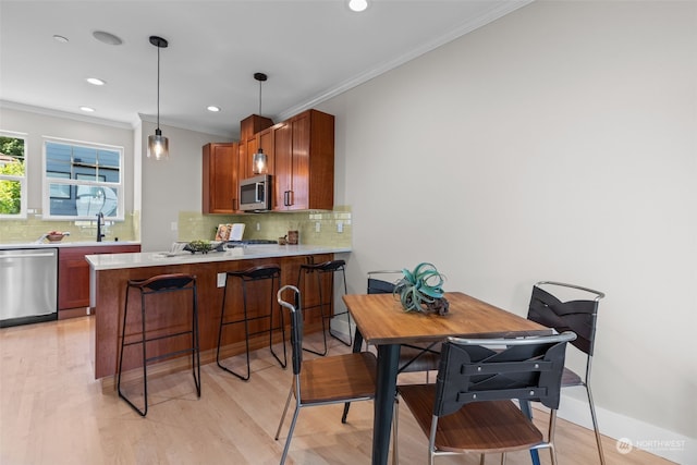 kitchen featuring ornamental molding, appliances with stainless steel finishes, kitchen peninsula, and sink