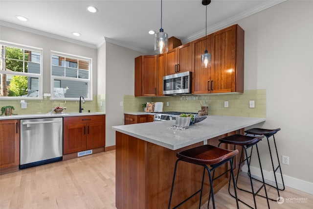 kitchen featuring stainless steel appliances, decorative light fixtures, kitchen peninsula, and light hardwood / wood-style floors