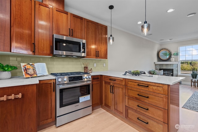 kitchen with hanging light fixtures, a high end fireplace, kitchen peninsula, stainless steel appliances, and crown molding