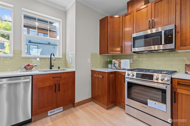 kitchen featuring tasteful backsplash, sink, ornamental molding, stainless steel appliances, and light hardwood / wood-style flooring