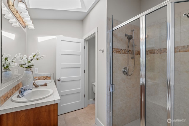 bathroom featuring a skylight, vanity, walk in shower, toilet, and tile patterned floors