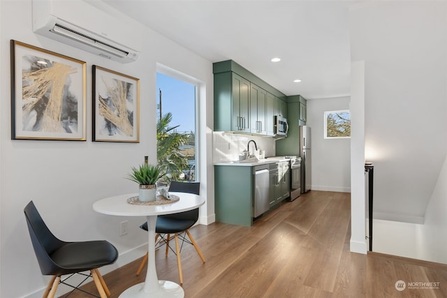 kitchen featuring plenty of natural light, stainless steel appliances, a wall unit AC, and green cabinetry