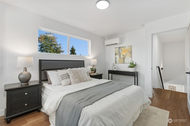 bedroom with an AC wall unit and hardwood / wood-style flooring