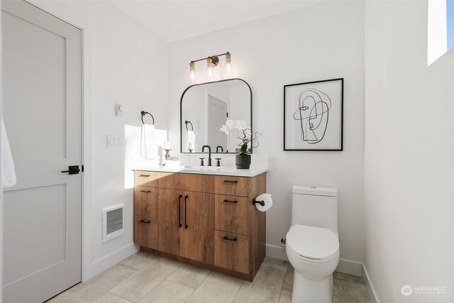 bathroom with toilet, vanity, and tile patterned flooring