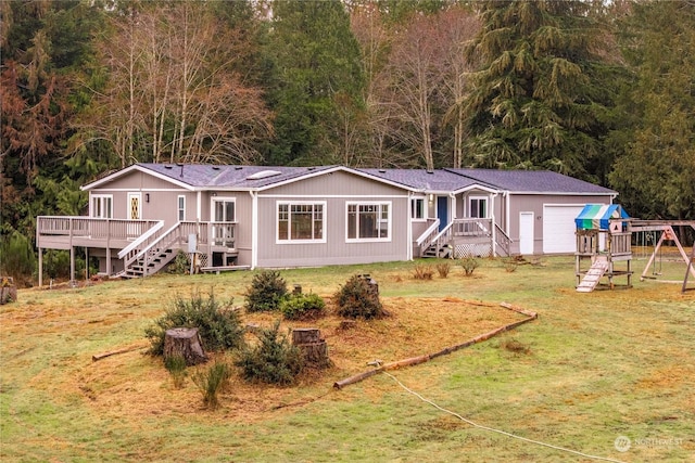 back of property with a playground, a garage, a wooden deck, and a yard