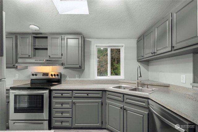 kitchen with a textured ceiling, stainless steel appliances, gray cabinetry, and sink