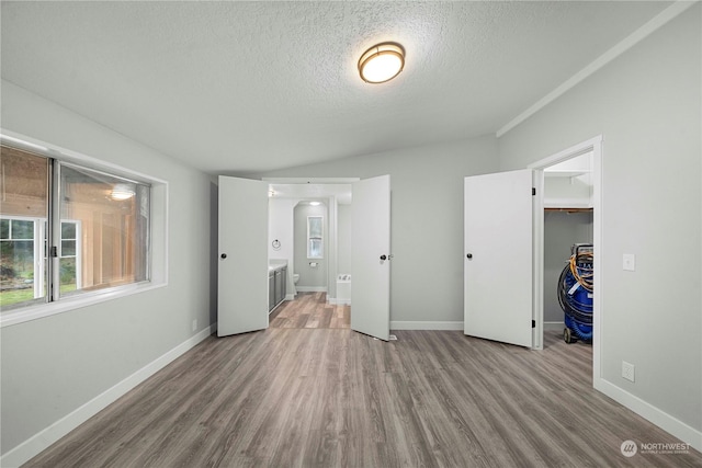 unfurnished bedroom featuring a spacious closet, light hardwood / wood-style floors, a textured ceiling, and a closet