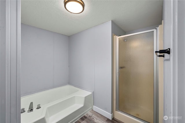 bathroom with a textured ceiling, independent shower and bath, and hardwood / wood-style floors