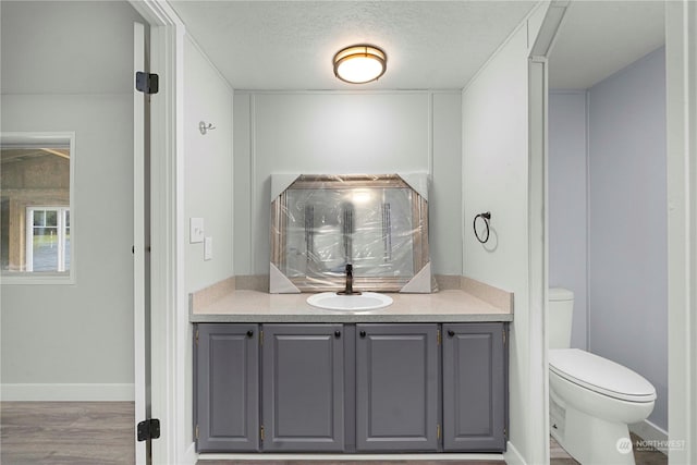 bathroom with toilet, vanity, a textured ceiling, and hardwood / wood-style flooring