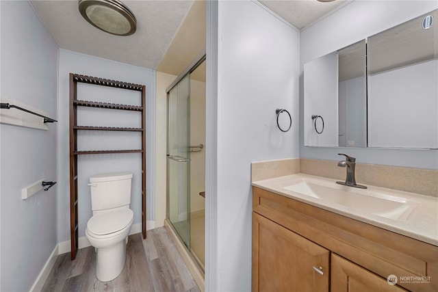 bathroom with an enclosed shower, toilet, a textured ceiling, and hardwood / wood-style floors