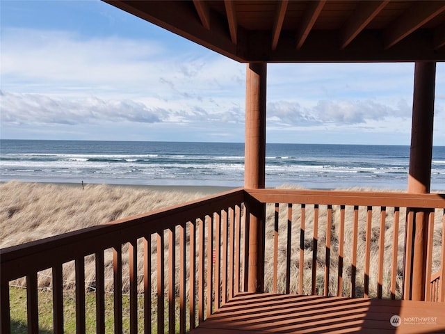 wooden terrace with a water view and a view of the beach