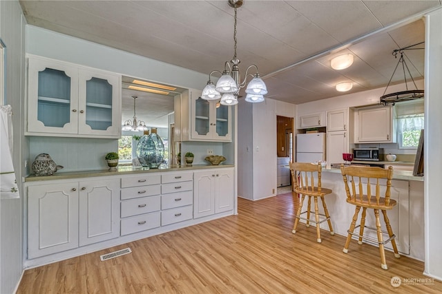 kitchen featuring white cabinetry, white fridge, and light hardwood / wood-style flooring