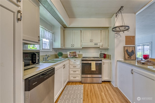 kitchen featuring white cabinetry, stainless steel appliances, sink, and hanging light fixtures