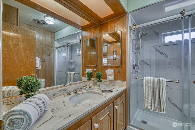 bathroom featuring vanity, wooden walls, and a shower with shower door