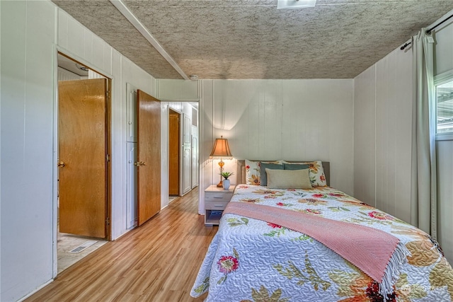 bedroom featuring light hardwood / wood-style flooring and wooden walls