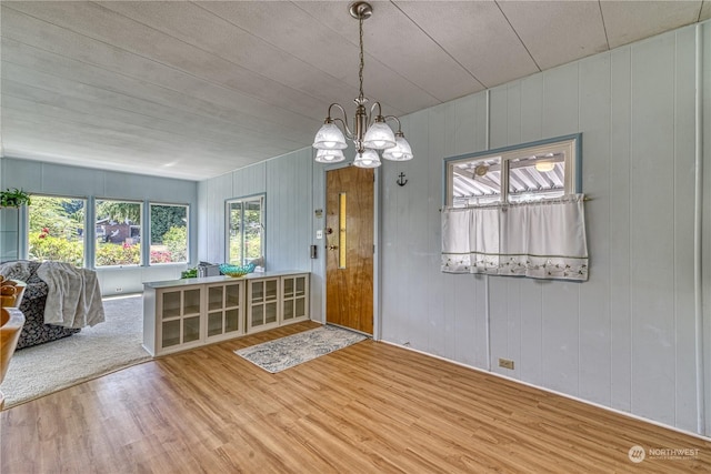 interior space with hardwood / wood-style floors, an inviting chandelier, and wood walls