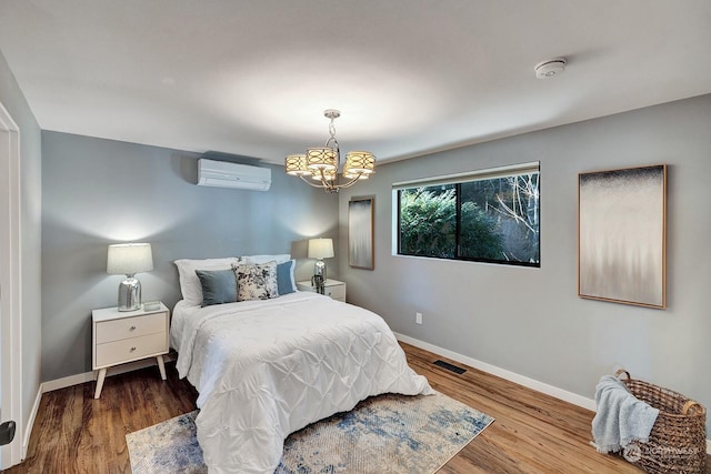 bedroom with a notable chandelier, hardwood / wood-style floors, and a wall unit AC