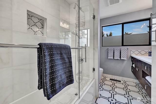 full bathroom featuring toilet, shower / bath combination with glass door, and vanity