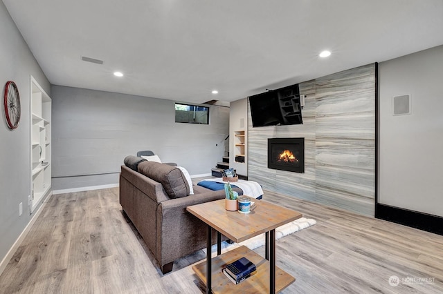 living room featuring light hardwood / wood-style floors, built in shelves, and a fireplace