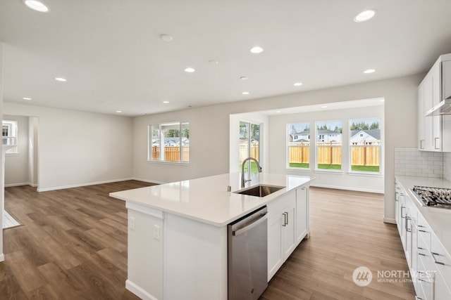 kitchen with appliances with stainless steel finishes, white cabinets, a center island with sink, and sink