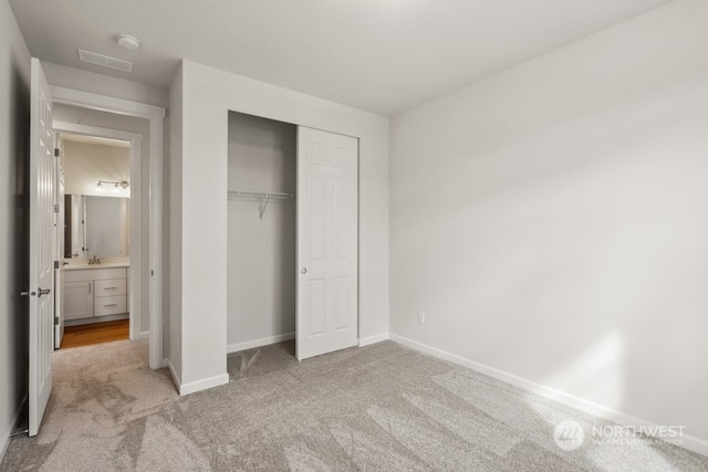 unfurnished bedroom featuring connected bathroom, a closet, and light colored carpet