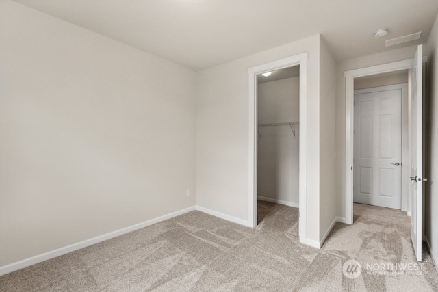 unfurnished bedroom featuring a spacious closet, a closet, and light carpet