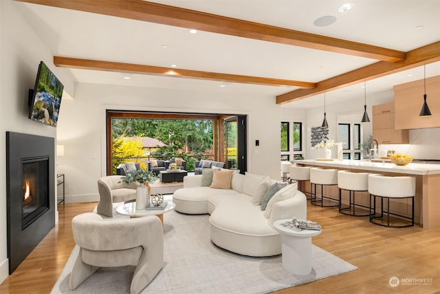 living room with sink, light hardwood / wood-style flooring, and beam ceiling