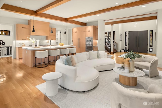 living room featuring light hardwood / wood-style floors, sink, and beam ceiling