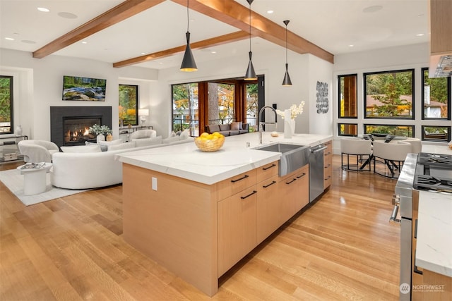 kitchen with pendant lighting, appliances with stainless steel finishes, beamed ceiling, sink, and light stone counters