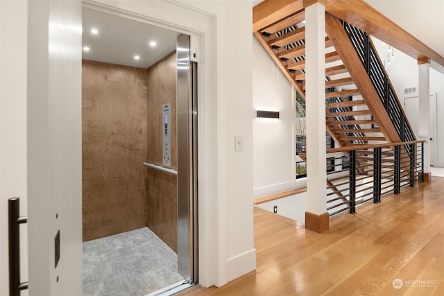 hallway featuring elevator and light hardwood / wood-style flooring