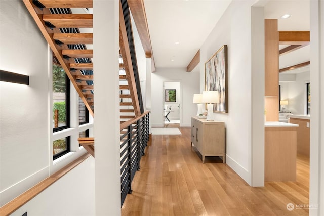 corridor featuring beamed ceiling and light hardwood / wood-style floors