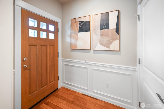 entrance foyer featuring wainscoting, light wood-type flooring, and a decorative wall