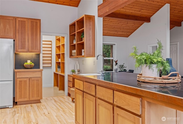 kitchen with white fridge, wood ceiling, backsplash, and sink