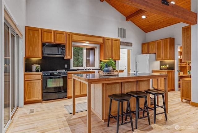 kitchen with a kitchen island, black appliances, decorative backsplash, beamed ceiling, and wood ceiling