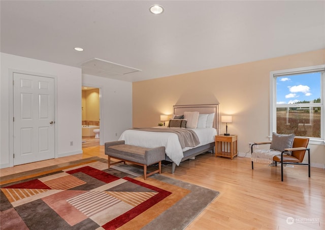 bedroom with connected bathroom and hardwood / wood-style floors