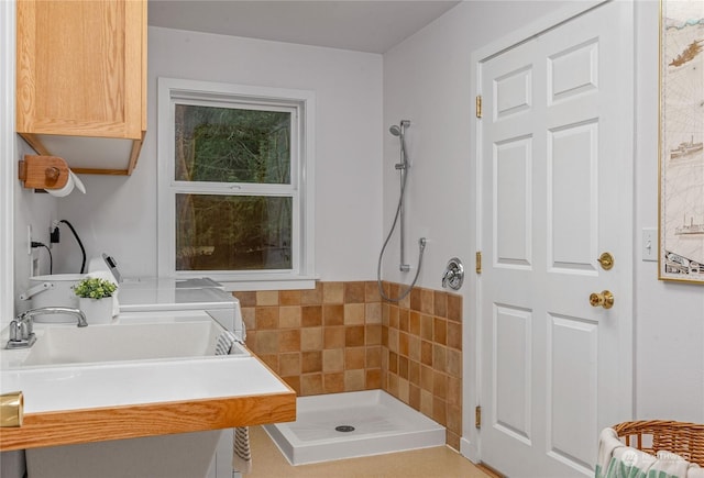 bathroom with a shower, washer and clothes dryer, and sink