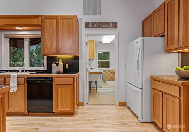 kitchen featuring tasteful backsplash, dishwasher, a wealth of natural light, and white fridge