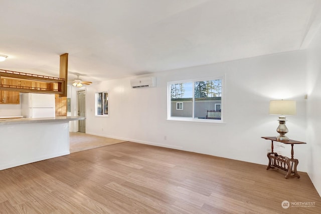 unfurnished living room featuring light hardwood / wood-style flooring, an AC wall unit, and ceiling fan