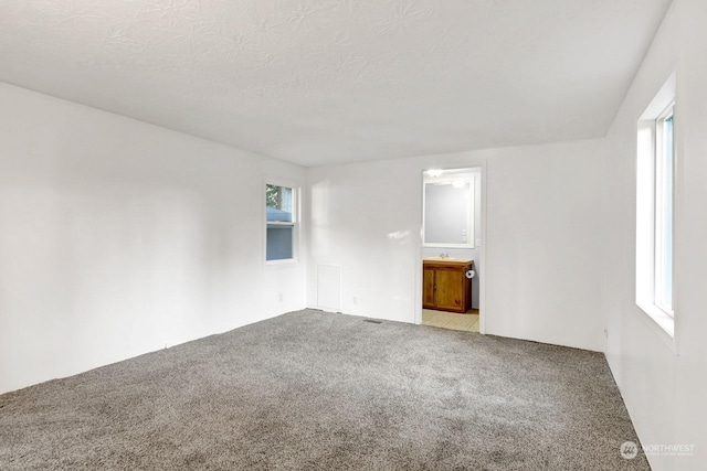 carpeted empty room with a textured ceiling