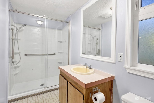 bathroom featuring a shower with shower door, a textured ceiling, toilet, and vanity