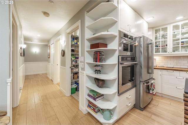 kitchen featuring light wood-type flooring, stainless steel appliances, white cabinetry, and butcher block countertops