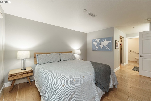 bedroom with connected bathroom and light hardwood / wood-style flooring